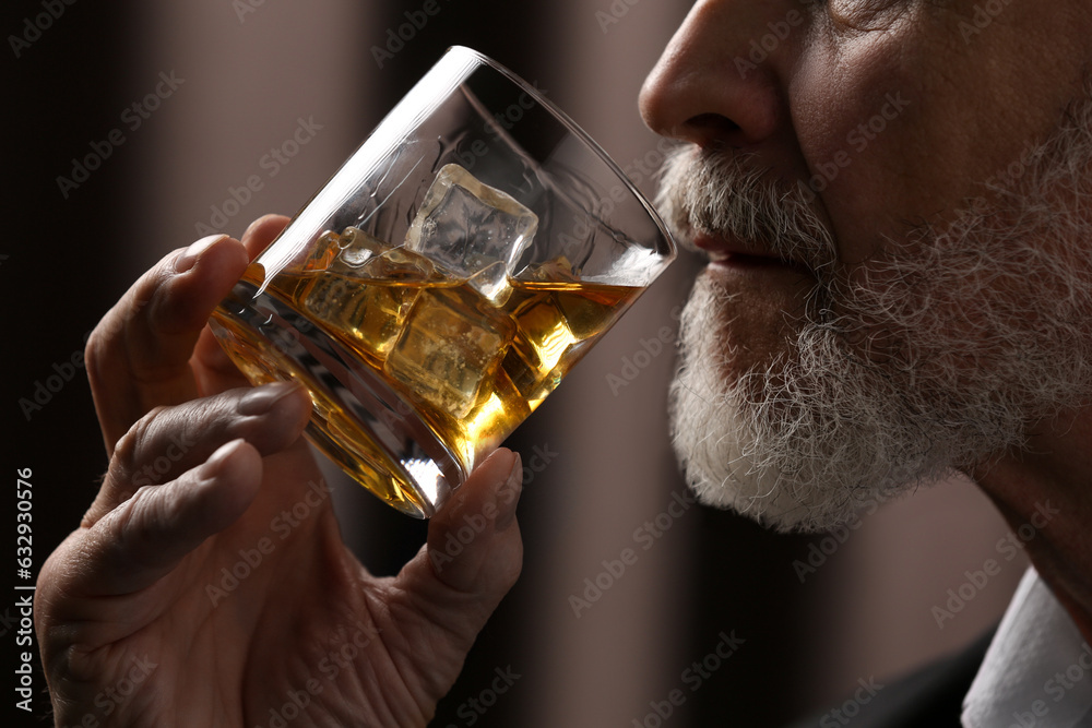 Wall mural Senior man drinking whiskey on brown background, closeup