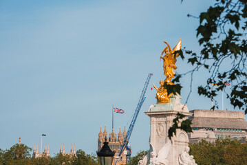 Naklejka premium The Golden Angel of Victoria Memorial. Buckingham Palace by famous statue of London. Big Ben Parliament with clear sky in background.