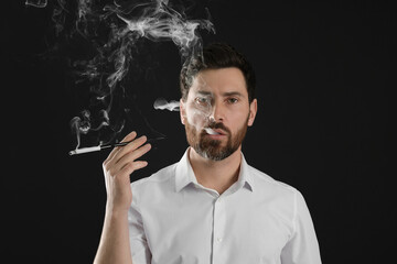 Man using long cigarette holder for smoking on black background