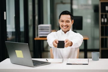 Confident Asian man with a smile standing holding notepad and tablet at the office.