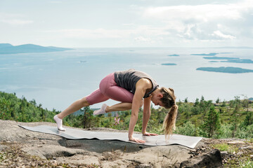 Young exercise woman yoga workout. The asana pose is harmony with nature. Uses mat meditation and mental health of a person, the trainer is engaged in asana Pilates and stretching a slim body.