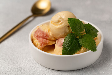 Peach ice cream with strawberry sorbet, decorated with a sprig of mint