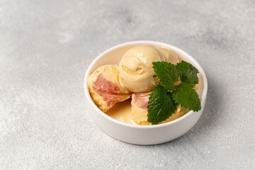 Peach ice cream with strawberry sorbet, decorated with a sprig of mint