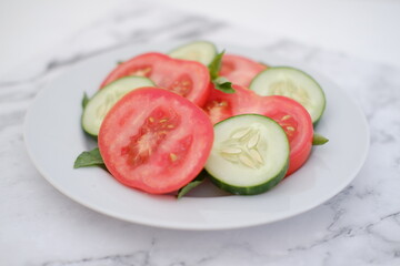 Tomato slices with basil leaves on a white plate. Selective focus.
