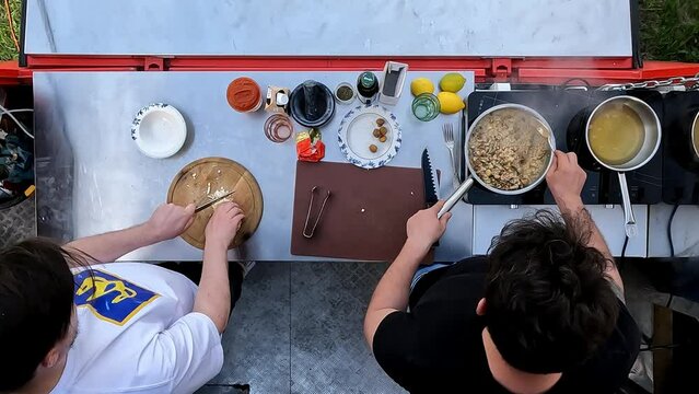 Top view image. Two men cooking outdoors, preparing delicious and healthy food. Outdoor kitchen. Concept of food, cuisine, hobby, taste, weekend activity, street cookery