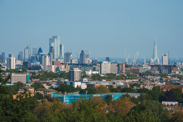 Scenic view of London cityscape with blue sky in background. Modern skyscrapers amidst residential buildings. High angle view of urban development in London.