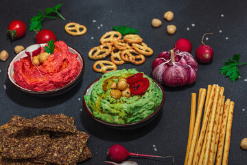 Various hummus dips, fresh vegetables and herbs. Crispy bread snacks, modern vegan healthy food