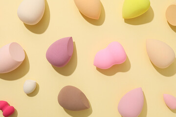 Cosmetic sponges on yellow background, top view
