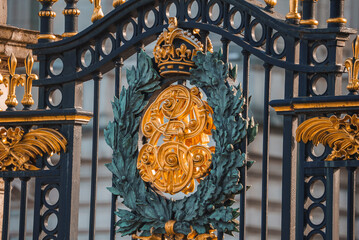 Closeup shot of shield on metal gate. Entrance of Buckingham Palace. Black and golden fence of...