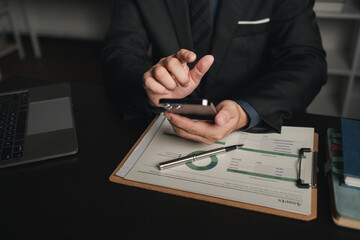 Businessman is in the office in the middle of night, he is holding his mobile phone, he is working overtime at a start-up company, he is working hard and overtime. Overtime concept. working at night