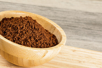 Wooden Bowl with fresh ground Roasted Coffee Grounds wooden background