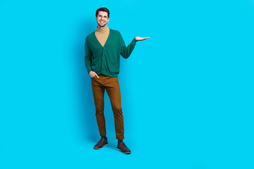 Full size body cadre of cheerful handsome guy hold demonstrate object much empty space advertising isolated on blue color background