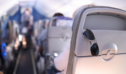 Sunglasses are placed on the passenger seat on plane. Summer vacation and travel concept