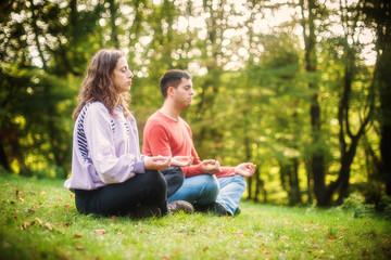 Fototapeta premium Young couple in everyday casual clothing doing yoga relax exercise in nature park outdoor