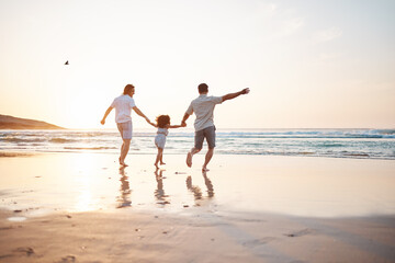 Gay couple on beach, men and child, playing together and holding hands at sunset, running in waves...