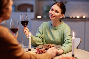 Portrait of young woman drinking wine with husband and enjoying romantic dinner at home
