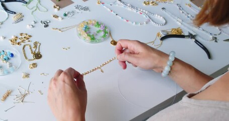 Female jewelry designer working in studio making necklace and earrings - Powered by Adobe