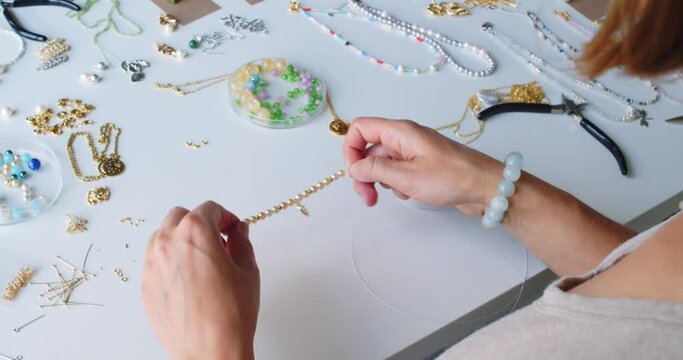 Female jewelry designer working in studio making necklace and earrings