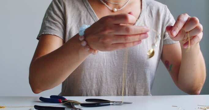 Female jewelry designer working in studio making necklace and earrings