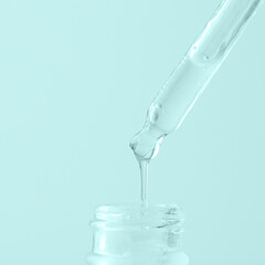 Pipette dropper with trasparent drop onlight blue background. Serum, collagen, enzyme, peptides,hyaluronic acid