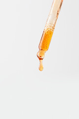 Abstract dropper pippete pouring orange drop into the glass bottle on white background.Skin care product presentation