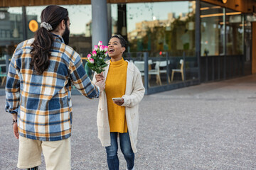 multiracial young couple on valentines day give flowers on the street