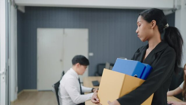Asian woman employee stressed and fed up after quitting her job. A women holding a box of things and very upset with fired. Woman was fired from the corporation. Unemployment, Dismissal