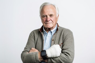 Medium shot portrait photography of a man in his 70s wearing a wrist brace because of a minor sprain wearing a chic cardigan against a white background 