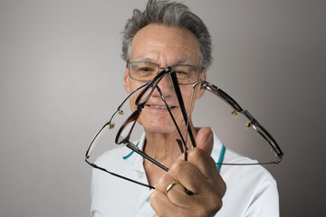 Mature Man checking out and holding up all his old prescription glasses