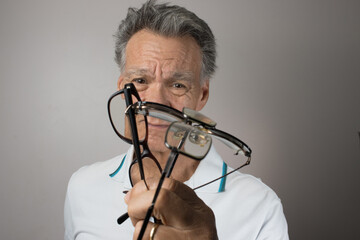 Mature Man checking out and holding up all his old prescription glasses