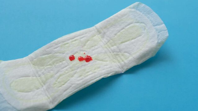 Women's sanitary pad with blood on a blue background close-up