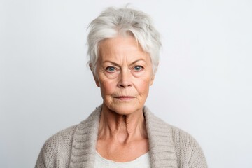 Medium shot portrait photography of a woman in her 60s with furrowed brows and a tense expression due to hypertension wearing a chic cardigan against a white background 
