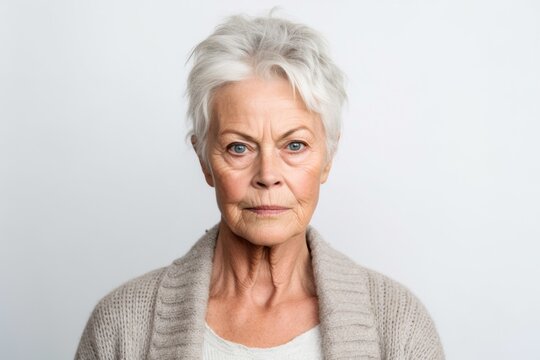 Medium shot portrait photography of a woman in her 60s with furrowed brows and a tense expression due to hypertension wearing a chic cardigan against a white background 