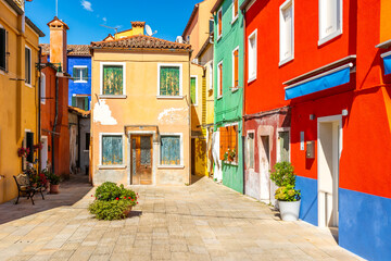 Fototapeta na wymiar Colourful houses and buildings on a quiet courtyard. Bright green shutters for the windows and clothes lines or wash lines with laundry. Burano, Venice, Italy
