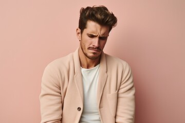 Medium shot portrait photography of a man in his 20s bent over and holding his stomach due to irritable bowel syndrome wearing a chic cardigan against a pastel or soft colors background 