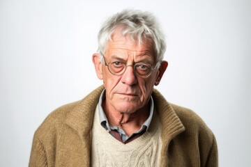 Medium shot portrait photography of a man in his 60s with a pained and tired expression due to fibromyalgia wearing a chic cardigan against a white background 