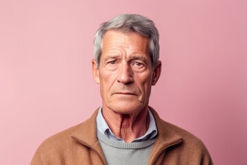Headshot portrait photography of a man in his 50s with a hint of fatigue due to chronic kidney disease wearing a chic cardigan against a pastel or soft colors background 