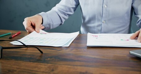 Trader observes paper reports of crypto trading charts growth at wooden table. Cryptocurrency market broker checks analysis of present cryptocurrency