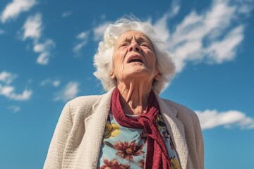 Medium shot portrait photography of a woman in her 90s coughing with discomfort due to pneumonia wearing a chic cardigan against a sky and clouds background 