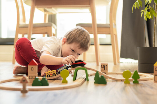 a child builds a wooden railroad on the floor, children's educational toys,