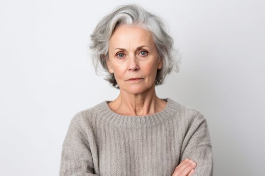 Medium shot portrait photography of a woman in her 50s showing tiredness and a worn-down expression due to chronic fatigue syndrome wearing a cozy sweater against a white background 