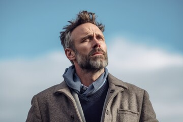 Fototapeta premium Medium shot portrait photography of a man in his 40s showing tiredness and a worn-down expression due to chronic fatigue syndrome wearing a chic cardigan against a sky background 