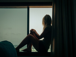 Silhouette of a woman looking at the sea from a window - Powered by Adobe
