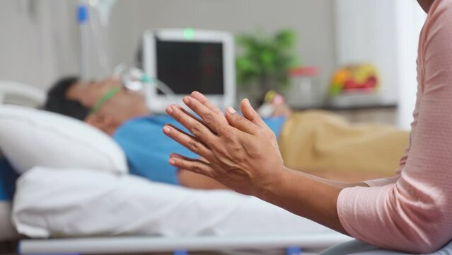 Close up shot of wife hands or family hands praying for admitted fathers health recovery at hospital near bed - concept of family caring, Emotional Bonding and togetherness