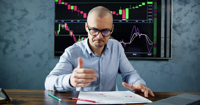 Trader struggles with analysis of cryptocurrency market on papers. Crypto market broker looks at statistics on papers against monitor with crypto charts