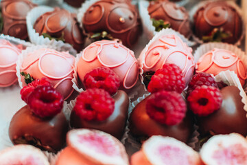 Pink chocolate covered strawberries with fresh raspberries on top. Candies and sweets collection. Tasty set for holidays