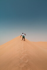 Fototapeta na wymiar Boy running up sand dune