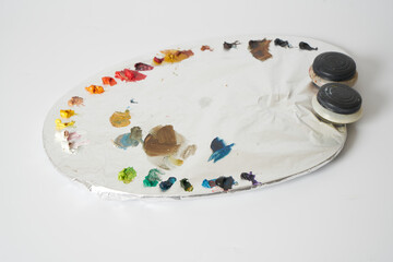 colorful oil paints on painters palette on white background
