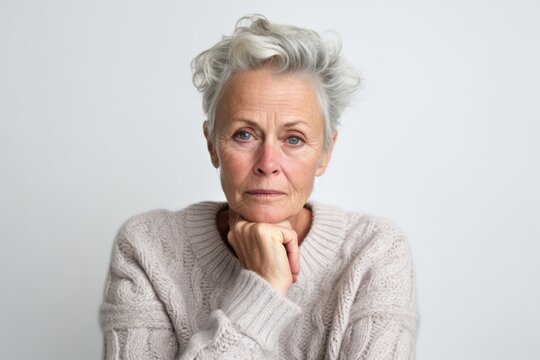 Medium shot portrait photography of a woman in her 50s visibly in discomfort and fatigue from an autoimmune disease like lupus wearing a cozy sweater against a white background 