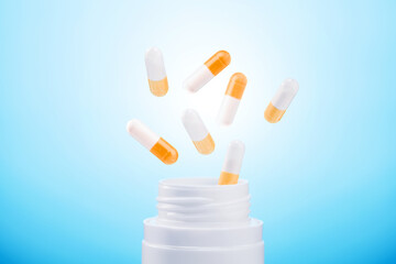  pills from plastic medicine bottle on blue background. group of antibiotic pill capsules fallling.